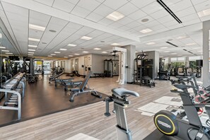 Een sportschool met diverse trainingsapparaten, waaronder loopbanden, krachttoestellen en losse gewichten.