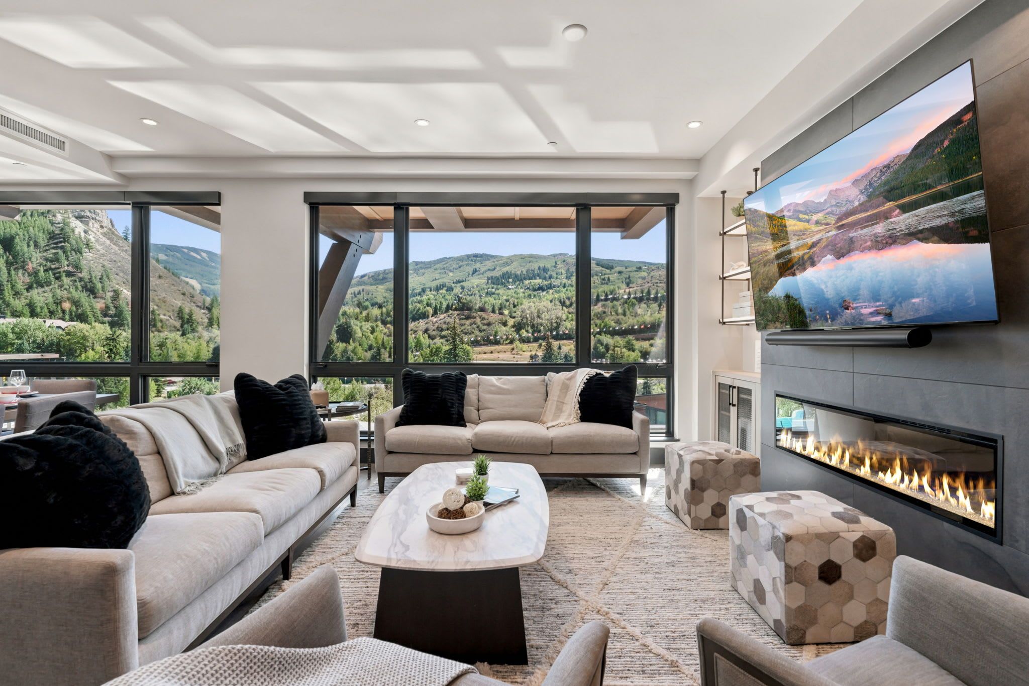 A modern living room with a fireplace, large windows, and a television.