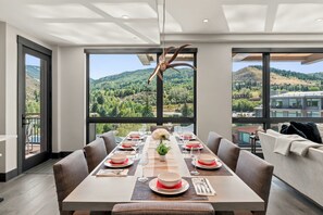 A dining area with a table set for six, large windows offering a view of a mountainous landscape. - Beaver Creek Penthouse - Luxe Amenities&Mtn Views (Avon)