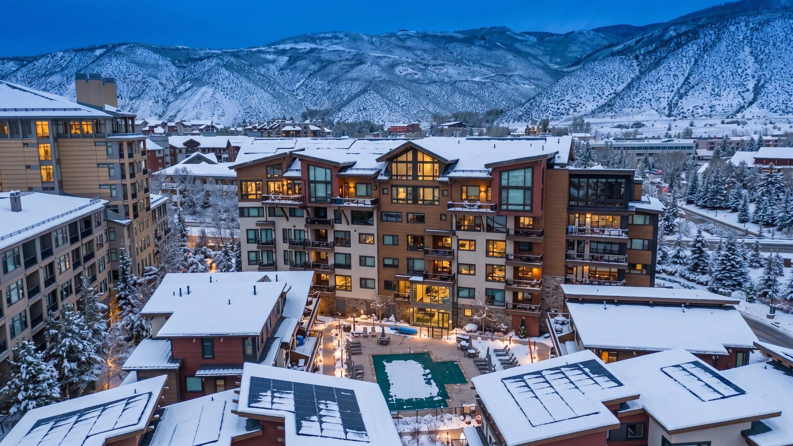 Un hôtel à plusieurs étages doté d’une cour intérieure, entouré de bâtiments et de montagnes couverts de neige.