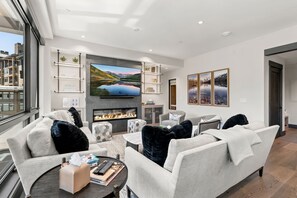 A modern living room with a fireplace, comfortable seating, a flat-screen TV, and a city view. - Beaver Creek Penthouse - Luxe Amenities&Mtn Views (Avon)