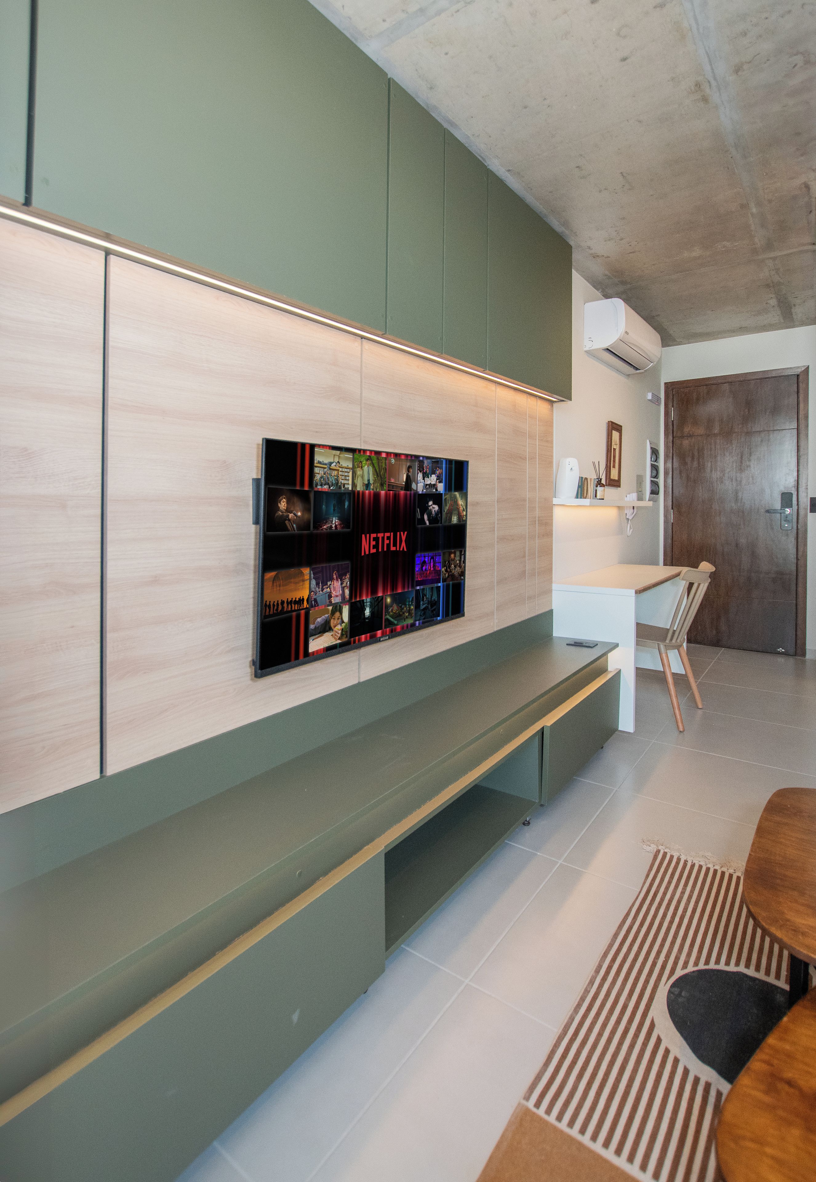 A modern interior with a wall-mounted television displaying Netflix content, a wooden bench, and a dining area with a table and chairs.