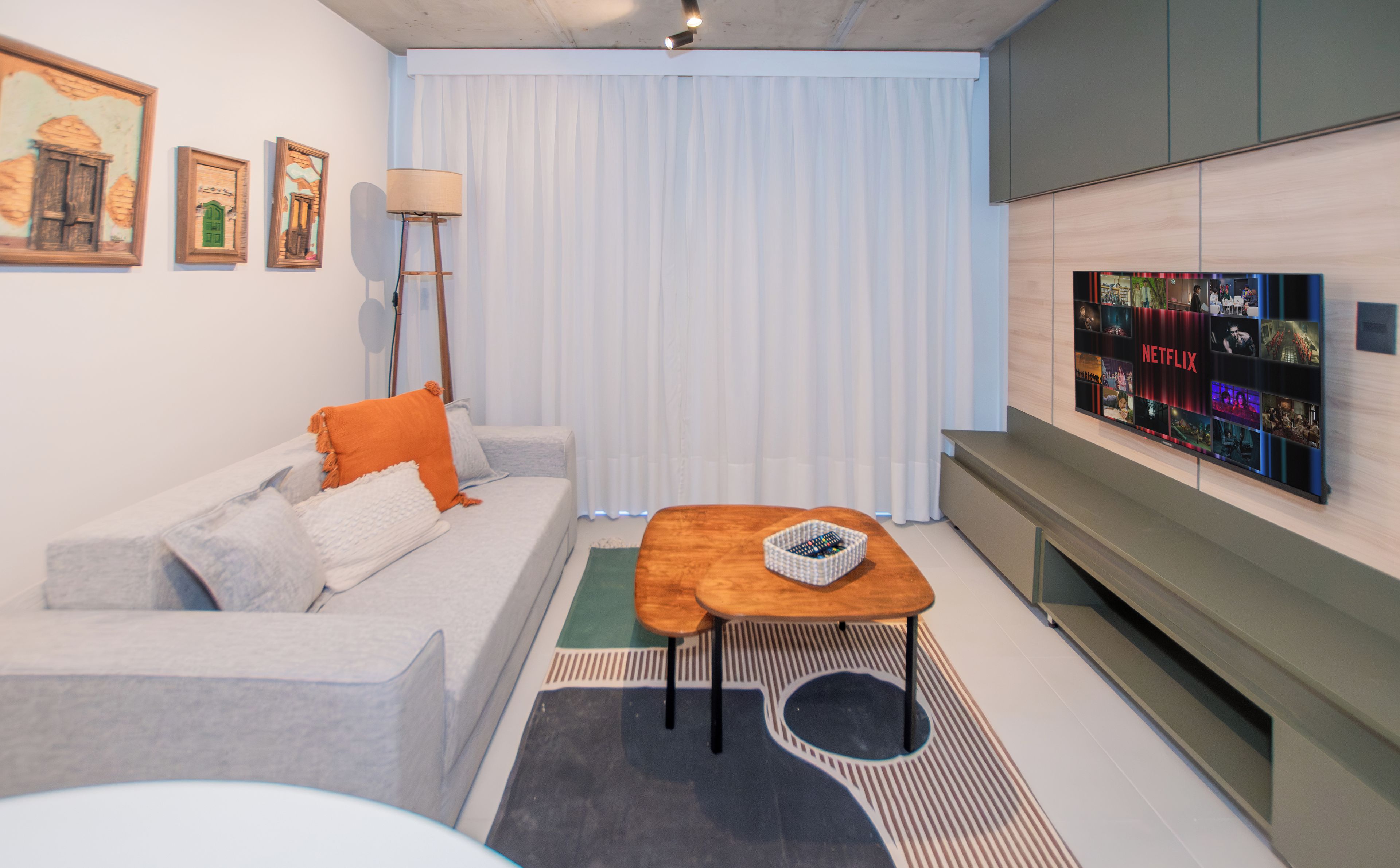 A modern living room with a sofa, a coffee table, a TV mounted on the wall, and a floor lamp.