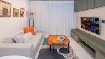 A modern living room with a sofa, a coffee table, a TV mounted on the wall, and a floor lamp.