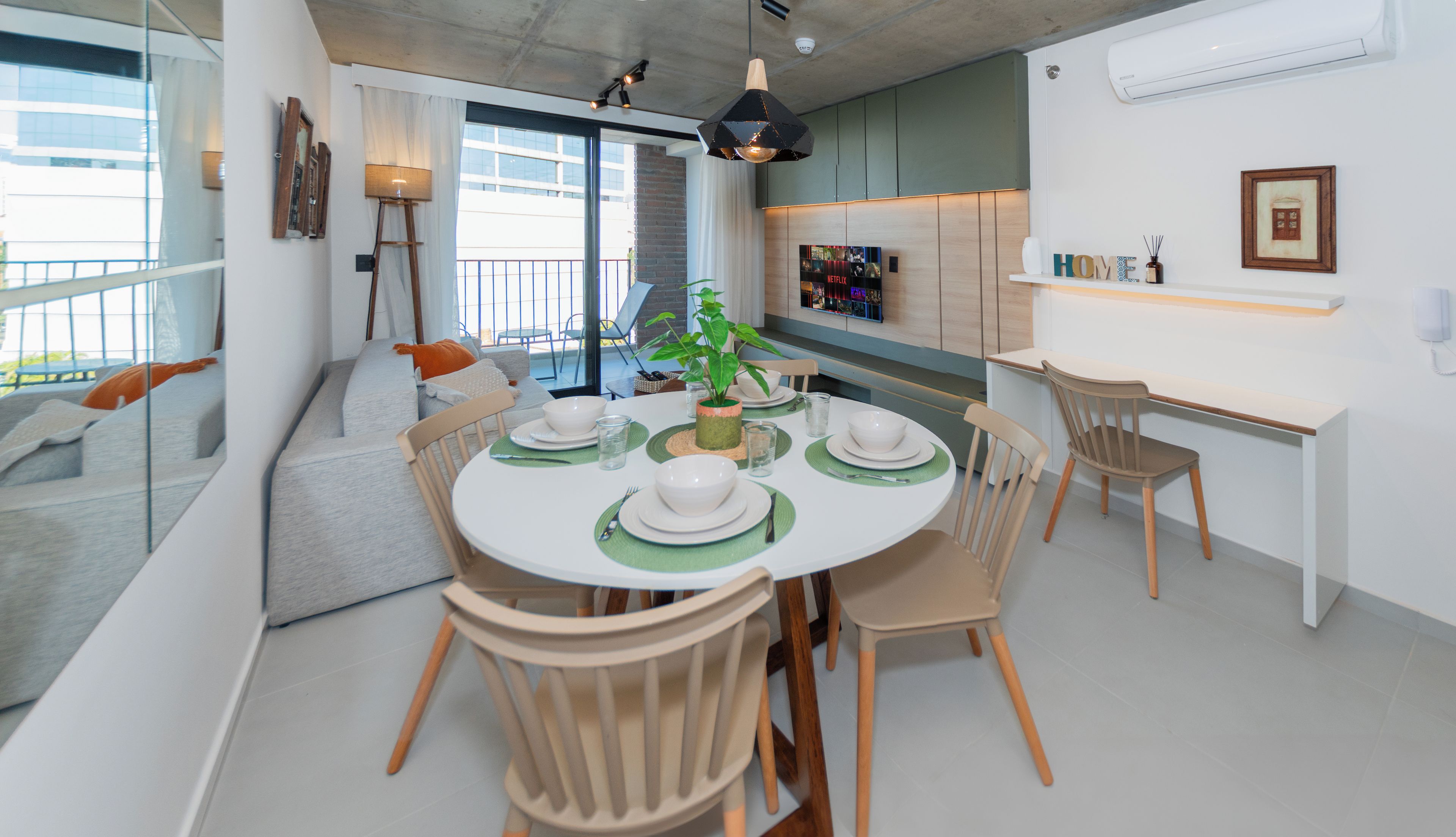 A modern dining area with a round table set for four, surrounded by wooden chairs.