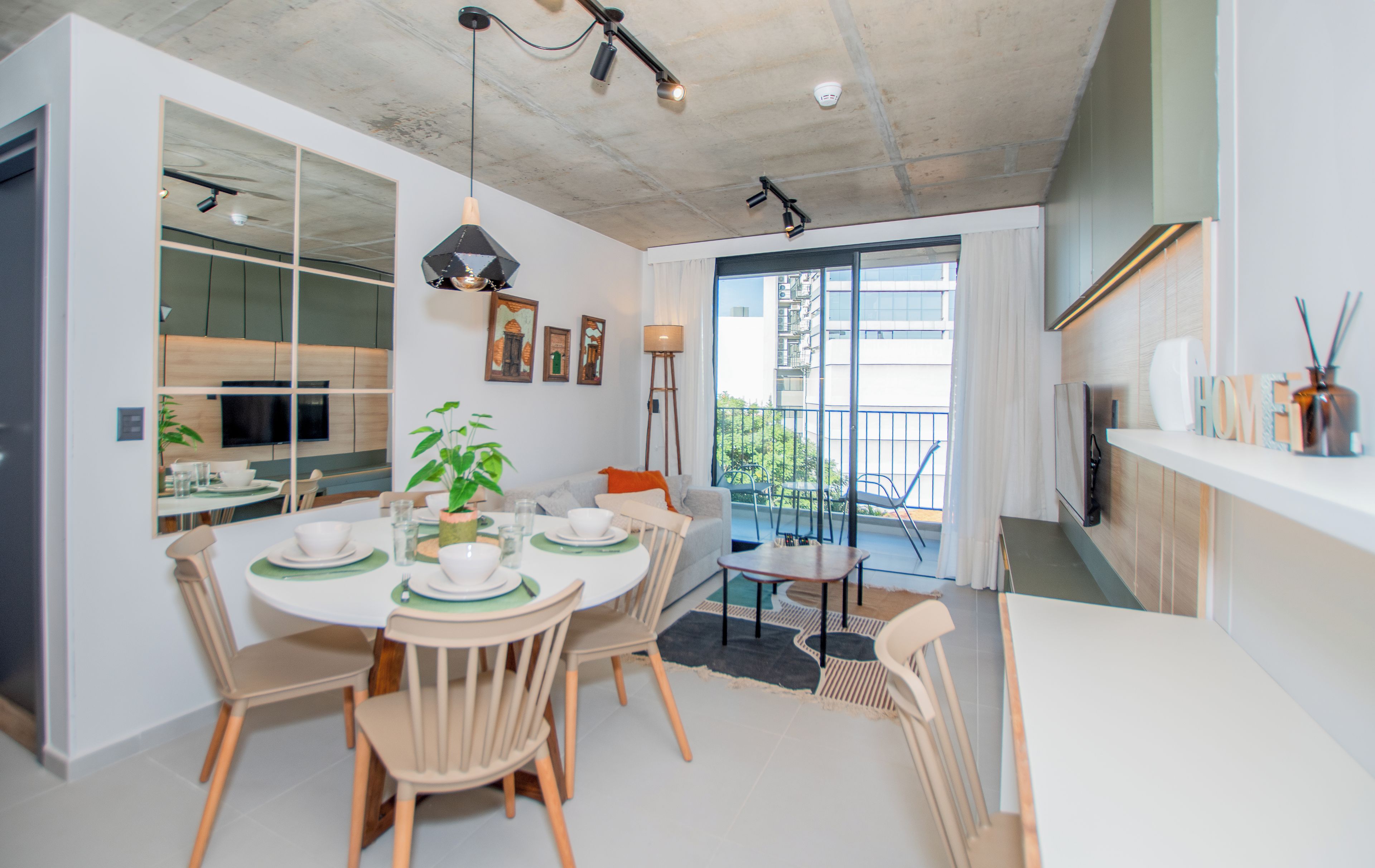 A modern dining area with a round table, chairs, and a potted plant.