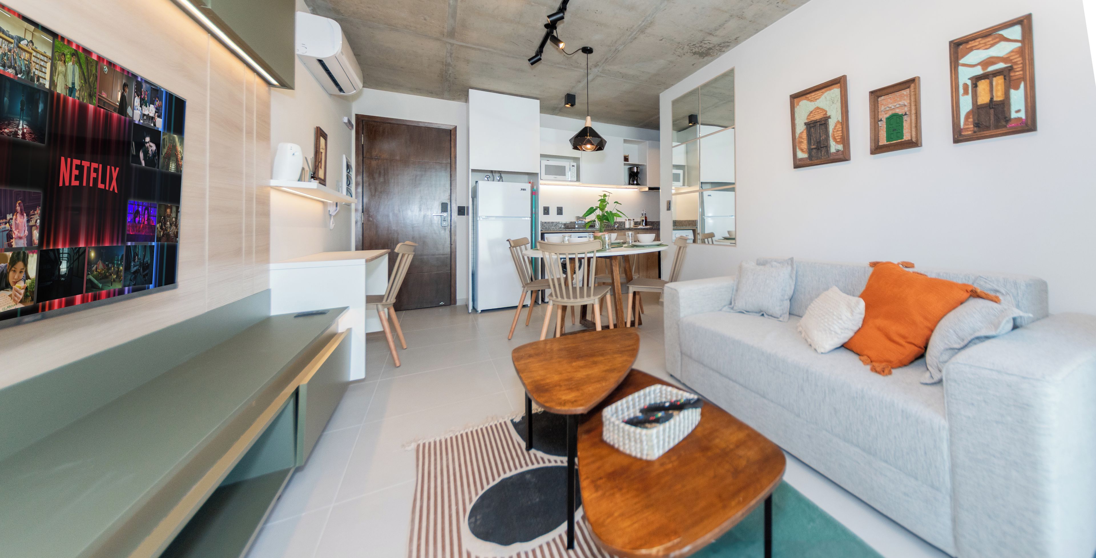 A modern living room with a sofa, coffee table, and a wall-mounted TV displaying Netflix content.