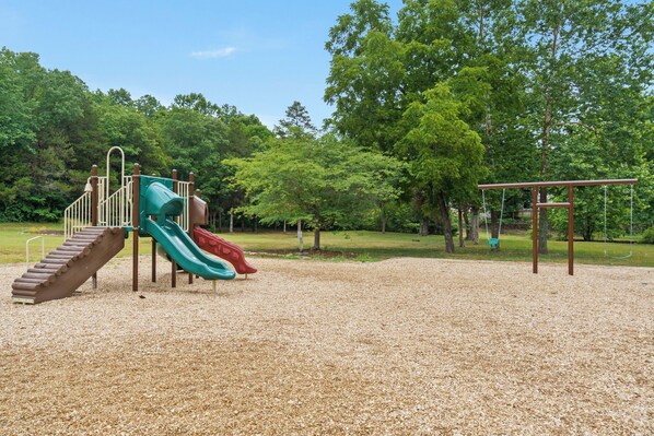 A playground with a slide and swings. - 2BR Condo Near SDC | Gated Resort Amenities (Reeds Spring)