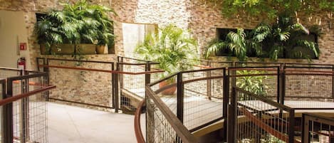 A multi-level atrium with a brick wall, metal railings, and potted plants.