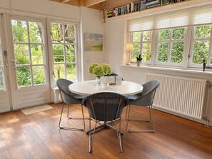A room with a round table, two chairs, a radiator, and a window with a view of greenery. - Unique Artist’s Atelier in Bergen | Near Dunes & Beach (Bergen)