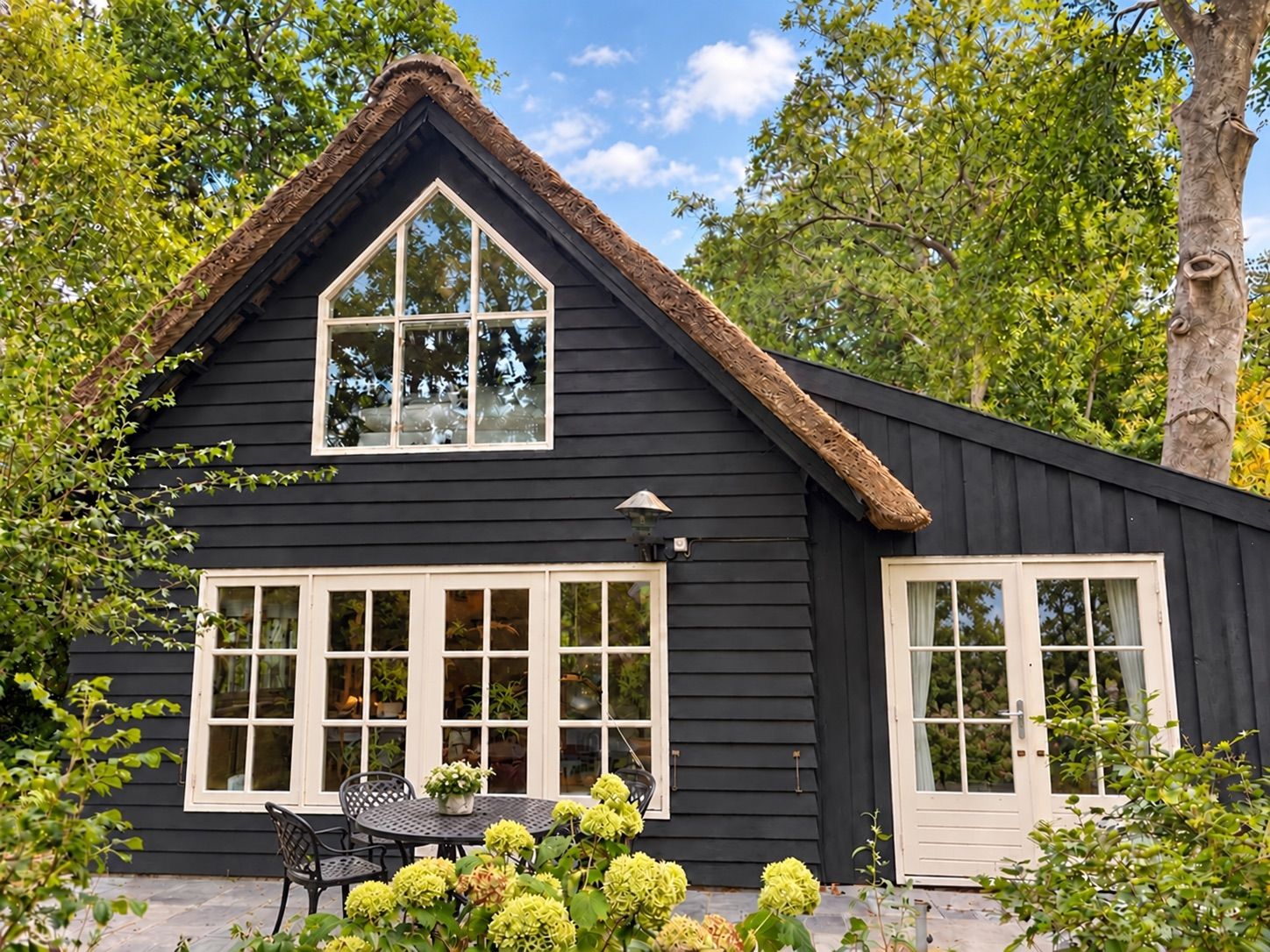 A black house with a triangular roof, large windows, and a door.