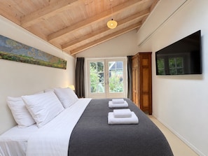 A bedroom with a bed, a painting, a TV, and a door leading to a balcony. - Unique Artist’s Atelier in Bergen | Near Dunes & Beach (Bergen)