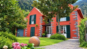 Ein rotes Haus mit Steinverzierungen, einem gepflasterten Weg und üppigem Grün.