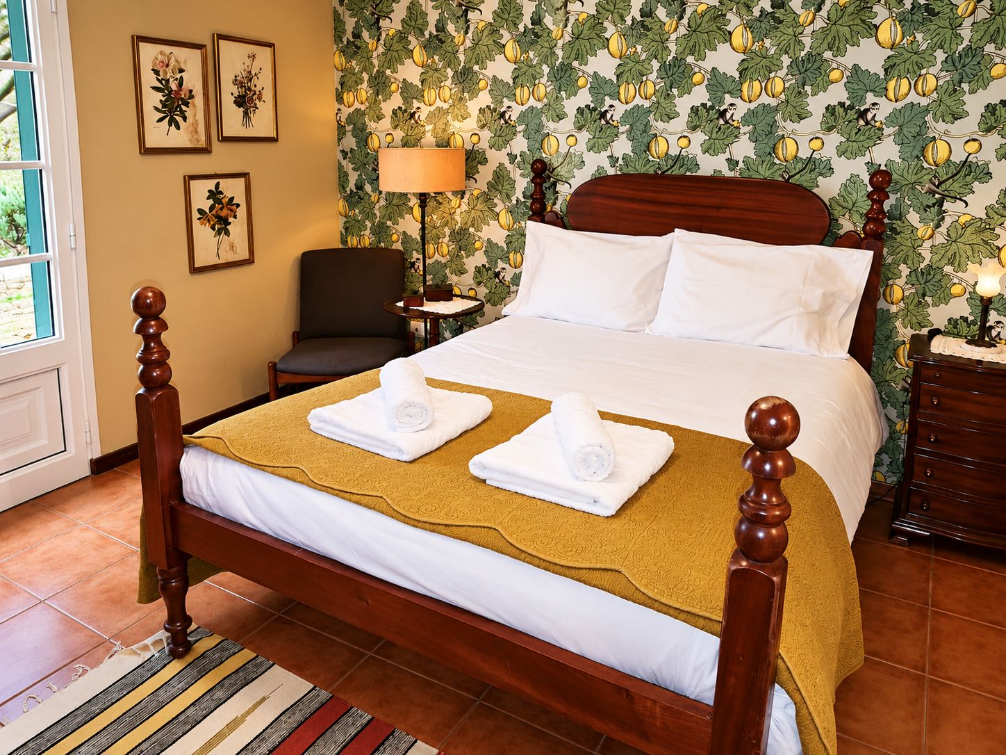 A hotel room with a large bed, a chair, a nightstand, and a window.