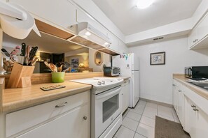 Eine kompakte Küche mit weißen Schränken, einem eingebauten Backofen, einer Mikrowelle und einem Toaster.