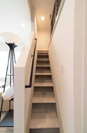 A staircase with a handrail and a light switch on the wall. - The Wanderlust Nest Tiny Home with Resort Access (Austin)