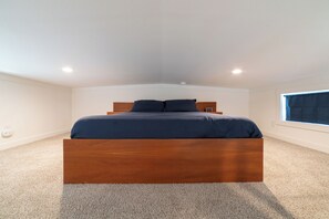 A bedroom with a wooden bed, a window with curtains, and a carpeted floor. - The Wanderlust Nest Tiny Home with Resort Access (Austin)