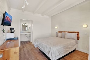 A bedroom with a bed, a desk with a computer, a television, and a bathroom with a mirror. - 11 Highlander (Williams)