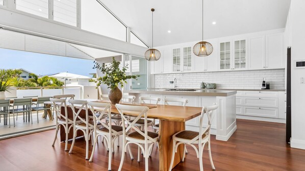 A modern kitchen with white cabinetry, a wooden dining table, and wicker chairs.