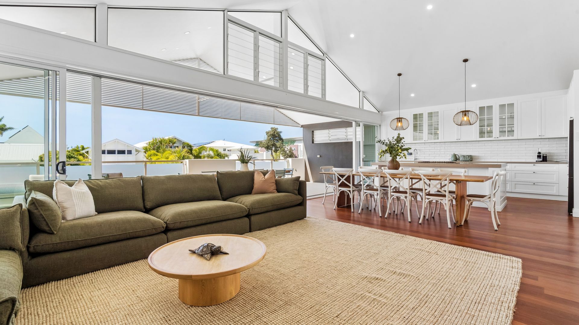 Un espacio moderno para vivir con un sofá modular, una mesa redonda de centro y un comedor con sillas y una mesa.
