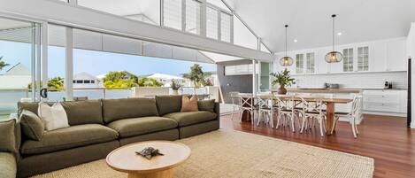 Un espacio moderno para vivir con un sofá modular, una mesa redonda de centro y un comedor con sillas y una mesa.