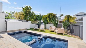 A backyard with a swimming pool, a hot tub, and outdoor seating.