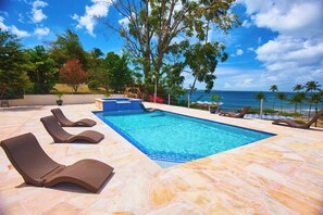 A swimming pool with lounge chairs, a small waterfall feature, and a view of the ocean. - Surfers Paradise Villa, front row seats to the most breathtaking beach sunsets. (Mt. Irvine)