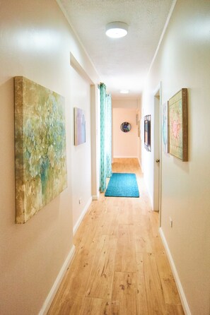 A hallway with wooden flooring, a blue rug, and artwork on the walls. - Surfers Paradise Villa, front row seats to the most breathtaking beach sunsets. (Mt. Irvine)