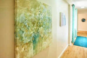A room with a large abstract painting on the wall, a blue mat on the floor, and a door with a patterned curtain.