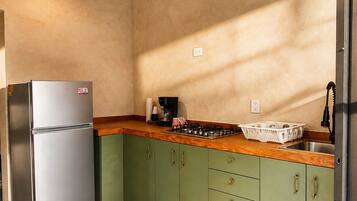 Una cucina con mobili verdi, un frigorifero in acciaio inossidabile, un piano di lavoro in legno e due lampade a sospensione.