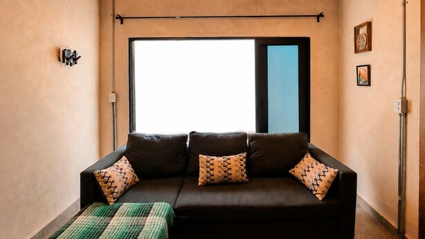 A cozy room with a brick ceiling, a large window, a black sofa with patterned cushions, and a green and white striped blanket on the floor. - House in Jalatlaco, pet-friendly and with a garage. (Oaxaca de Juárez)