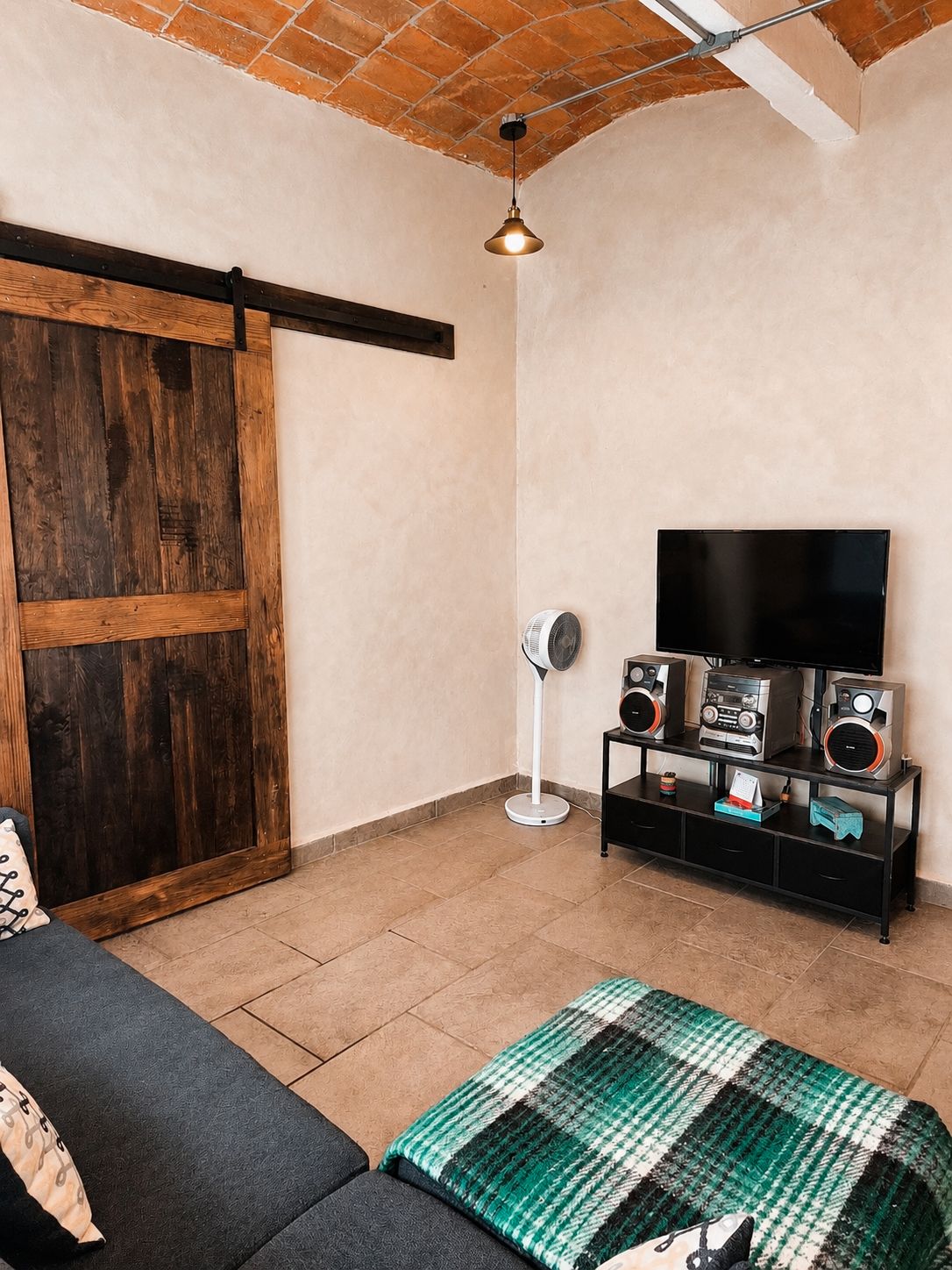 Un soggiorno con porta scorrevole, televisione a schermo piatto, impianto audio, ventilatore e divano.