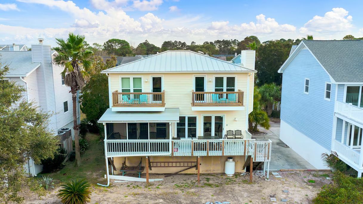A two-story house with a balcony on the second floor and a covered porch on the ground floor.