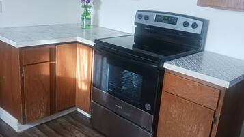 Una cucina con mobili in legno, un piano cottura in acciaio inossidabile e un ripiano di lavoro bianco.