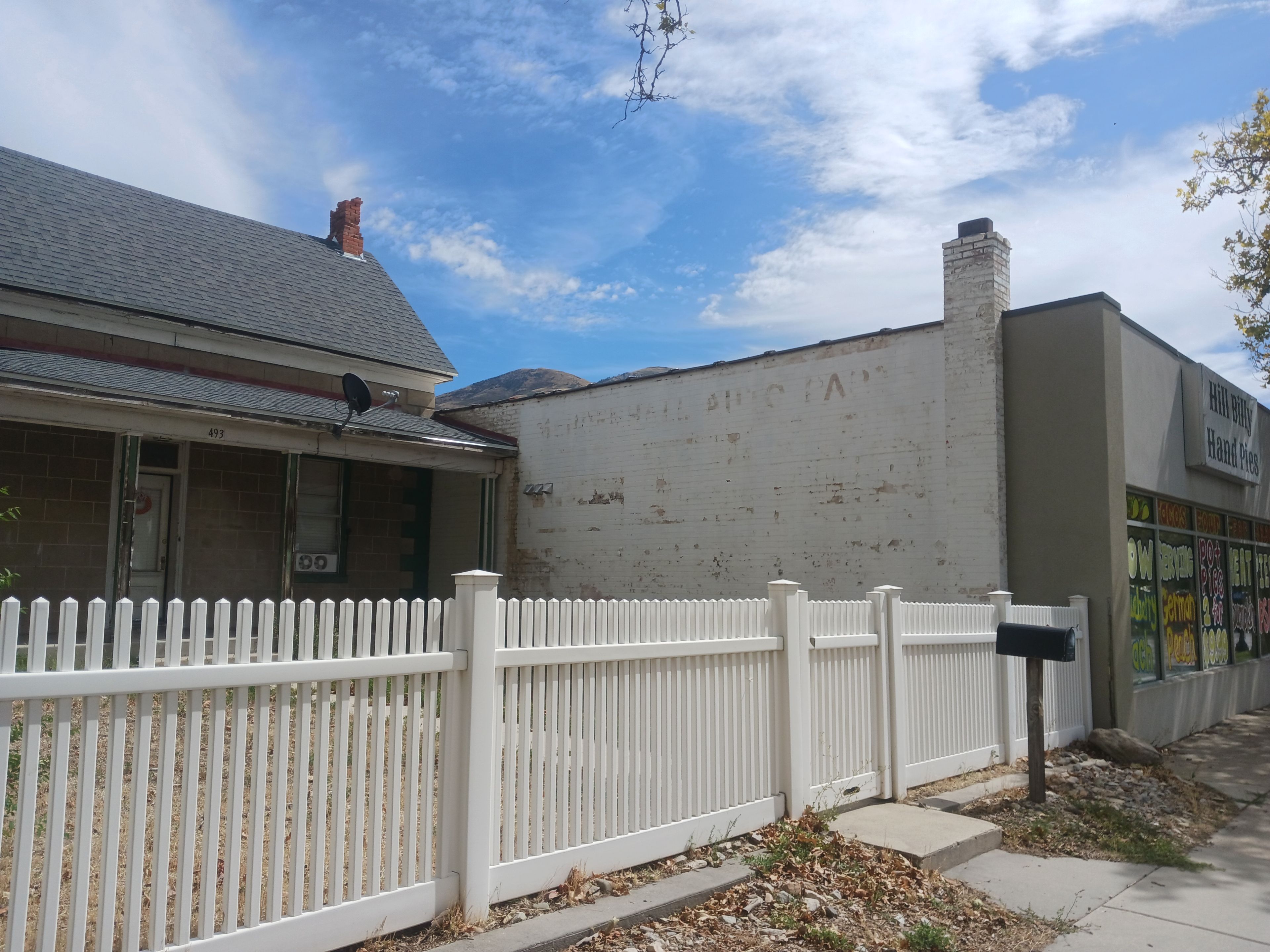 A building with a white picket fence, a brick facade, and a clear sky.