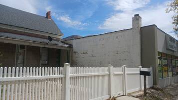 A building with a white picket fence, a brick facade, and a clear sky.