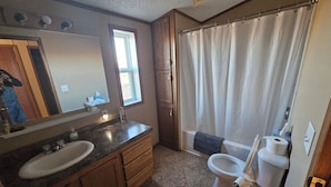 A bathroom with a sink, mirror, toilet, and shower curtain. - Wonderful 3-bedroom mobile home with AC in Hyannis (Hyannis)