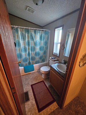 A bathroom with a bathtub, toilet, sink, and a shower curtain.