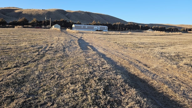 A rural landscape with a single house, a clear sky, and a hilly backdrop. - Wonderful 3-bedroom mobile home with AC in Hyannis (Hyannis)