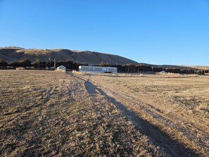 A rural landscape with a single house, a clear sky, and a hilly backdrop.