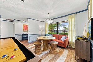 A room with a pool table, a red sofa, a dining table, and a window with curtains. - Sports Court • Putt Putt • Gym • Pool • Hot Tub (Bradenton)