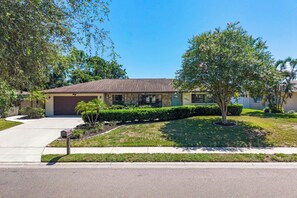 A single-story house with a garage, a well-maintained lawn, and mature trees. - Sports Court • Putt Putt • Gym • Pool • Hot Tub (Bradenton)
