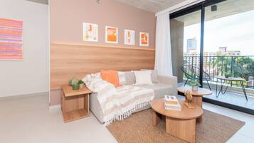 Una sala de estar moderna con un sofá, una mesa de centro y vistas a un balcón con mobiliario exterior.