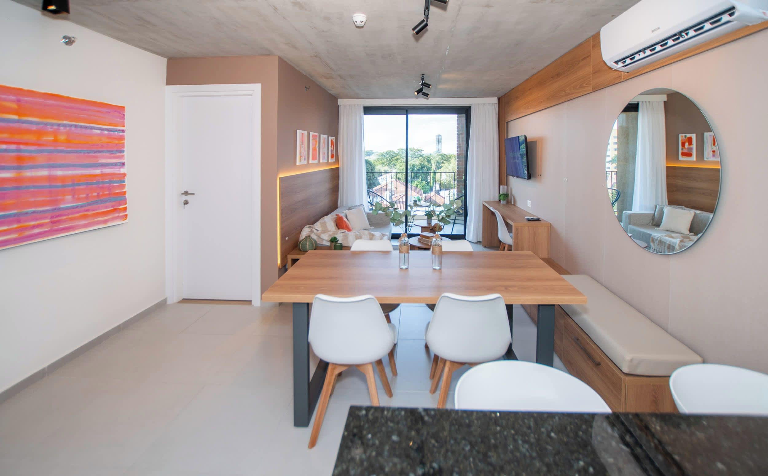Un interior moderno con una zona de comedor, un espejo grande y vistas al exterior.