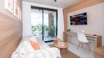 Una sala de estar moderna con un sofá, una mesa de centro, un escritorio con una silla y una amplia pantalla de televisión mostrando contenido de Netflix.