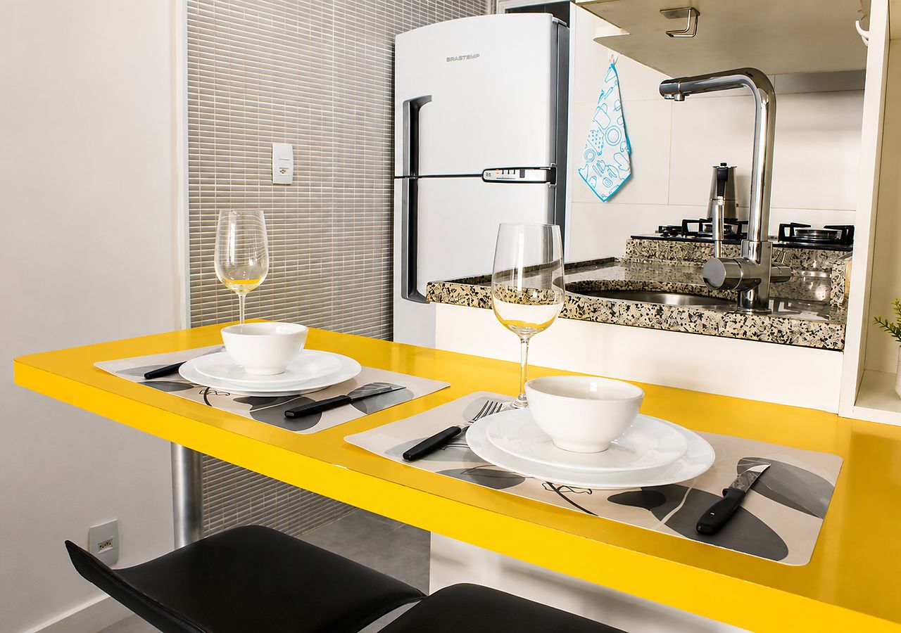 A compact kitchen with a modern refrigerator, a sink, and a countertop with a patterned backsplash.