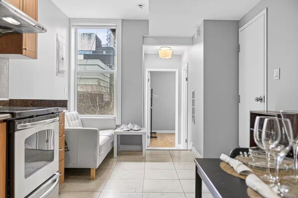 A modern kitchen with a built-in oven, a dining area with a table and chairs, and a view through a window. - Cozy Toronto 3BR Escape | Spacious Family Friendly (Toronto)