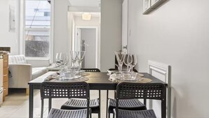 Comedor con una mesa dispuesta para cuatro personas, con vasos transparentes y sillas negras perforadas.
