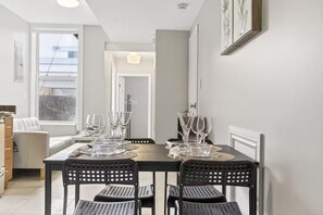 A dining area with a table set for four, featuring clear glassware and black perforated chairs. - Cozy Toronto 3BR Escape | Spacious Family Friendly (Toronto)