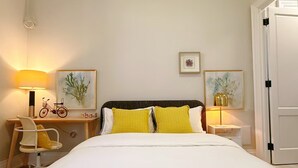 Quarto de hotel bem organizado, com uma cama, duas mesas de cabeceira, uma cadeira e uma escrivaninha.